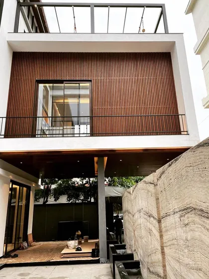 A residential facade nearing completion, highlighting the installation of the vertical wood paneling. This image captures a key moment in the construction process where a major design element is being put into place.