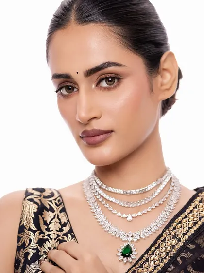 For a modern reception or cocktail event, I often suggest a sleek, layered diamond necklace. This piece, with its brilliant-cut stones and a striking emerald drop, offers a sophisticated sparkle that is both contemporary and timeless.