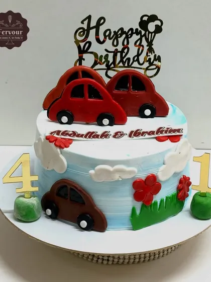 A cute car theme cake for a joint birthday celebration. This cake is decorated with simple, colourful fondant cars on a sky-blue background.
