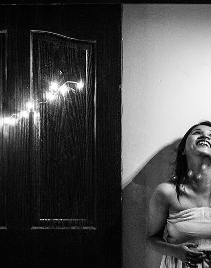 A portrait of pure elation, with the subject looking up towards the light. The fairy lights add a touch of magic to this black and white image.