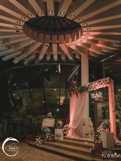 This welcome area was designed to blend with the venue's modern architecture. A soft pink floral arch and elegant signage greet guests as they ascend the steps.
