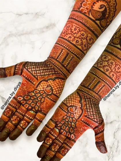 This full-sleeve bridal mehendi showcases stunning peacock motifs. The intricate feather patterns and detailed line work create a sense of movement and elegance.