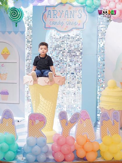 The birthday boy, Aryan, sits atop a giant ice cream cone prop at his "Candy Shop" party. Our themed props make for fantastic photo opportunities and add to the immersive experience.