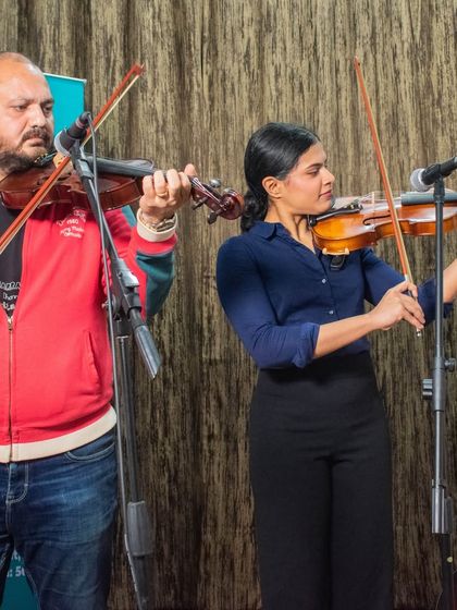 A photo of a violin duo, a teacher and student, performing together at the HSR open mic.