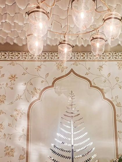 A view looking up at the elegant glass chandelier and the custom wallpapered backdrop. The design is a study in sophisticated patterns and textures.
