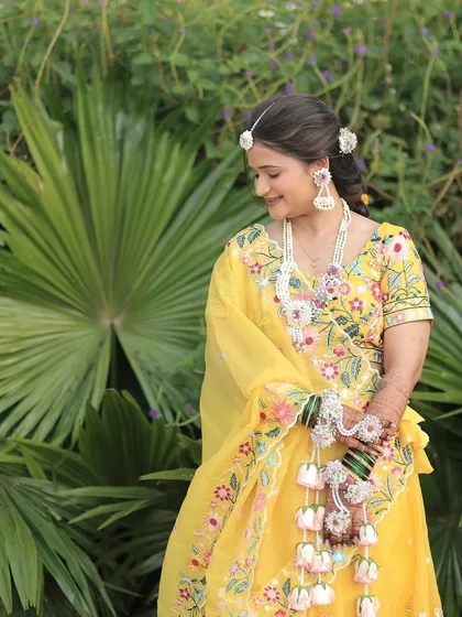 A smiling bride at her Haldi ceremony, wearing a custom set of floral jewellery with delicate pink rose kaliree.