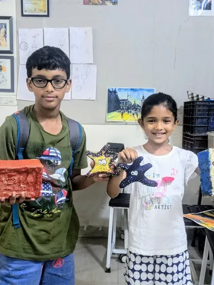 Neil and Naomika with their finished pieces from the papermache class. They made a brick, starfish, and a fabric-textured piece, showing the versatility of the medium.
