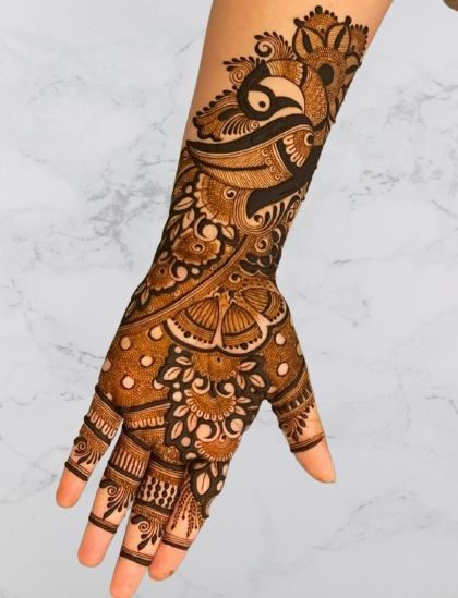 A classic Arabic-style design featuring a prominent peacock motif on the back of the hand, with patterns extending up the arm.