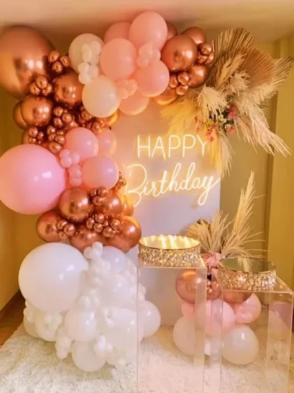 A gorgeous blend of rose gold, pink, and white balloons for a chic and feminine birthday celebration. The clear plinths and plush white rug add a touch of luxury to the decor.