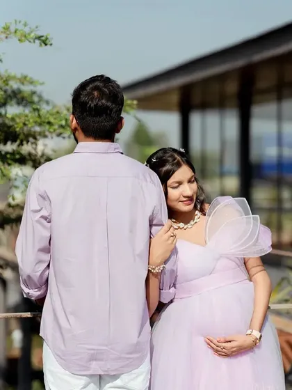 A quiet, romantic moment. The soft lavender color of the gown and the natural outdoor setting create a peaceful and serene mood.
