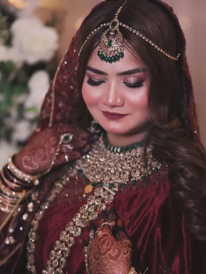 This bride's maroon velvet outfit is paired with stunning green and gold jewellery. I created a soft glam look with a matching maroon lip to tie everything together.