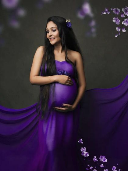 This flowing purple drape, accented with floral details, creates a vibrant and artistic maternity portrait.