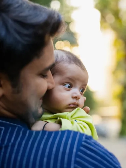 A baby looking over his father's shoulder, curiously taking in the world. These little moments of discovery are wonderful to capture during newborn and family events.
