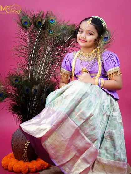 A full-length portrait showing her beautiful langa davani and the elegant peacock feather props.