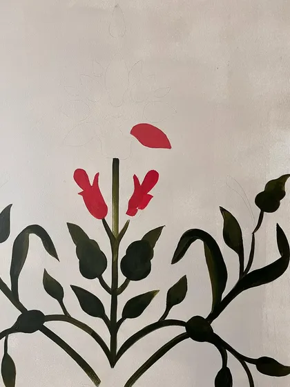 The beginning of a Mughal motif, with the first red petals being painted. This shows the careful, piece-by-piece construction of the intricate design.