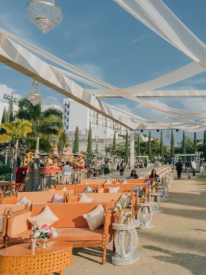 A wide view of an outdoor lounge area, with comfortable seating under a draped canopy and crystal chandeliers. Guest comfort is a top priority in my event designs.