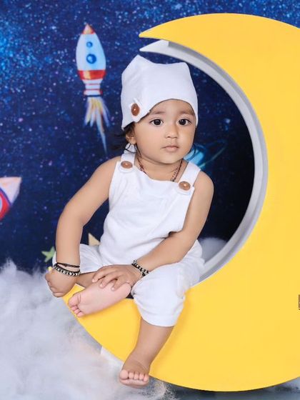 A little astronaut sits on a crescent moon against a starry galaxy backdrop. This creative space-themed shoot is perfect for adventurous little dreamers.