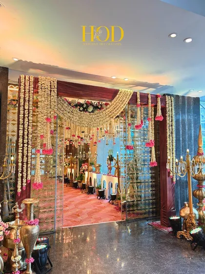 A stunning entrance view looking into the venue, framed by hanging floral strings and traditional candelabras, offering a glimpse of the celebration inside.