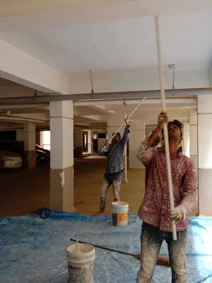 Our team at work on a large commercial project, painting the ceiling of an apartment building's parking garage. We use rollers with long extensions to ensure even coverage on high ceilings and large surfaces.