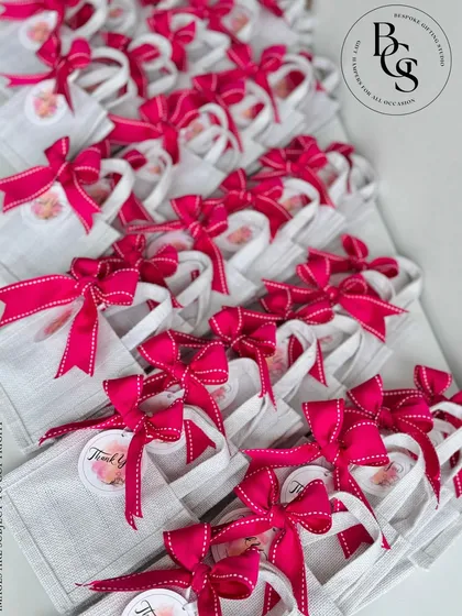 These small linen tote bags with bright pink ribbons are a practical and stylish return gift. Guests can reuse the bag, making it a gift that keeps on giving long after the event is over.