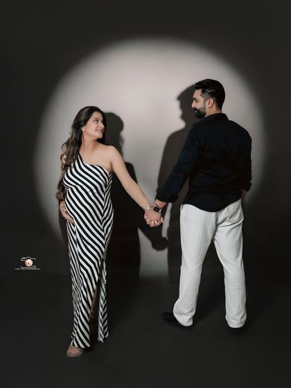 A creative studio shot using a spotlight to create dramatic shadows. The couple holds hands, their shadows stretching out behind them, adding an artistic and modern flair.