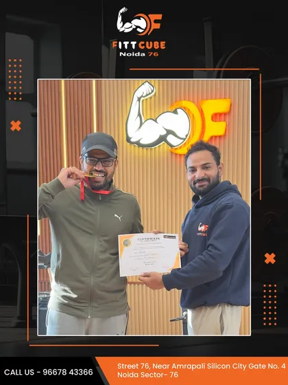 Celebrating another member's achievement. Here, one of our clients proudly holds his certificate and medal, marking a personal milestone in his fitness journey with his trainer by his side.