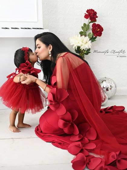 A sweet kiss between mother and daughter. These are the tender, fleeting moments that you'll want to remember forever, captured beautifully in matching red outfits.