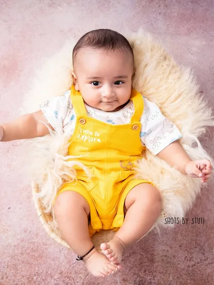 At three months, babies can hold their head up and interact more, allowing for a wider variety of poses. This little explorer in his yellow overalls is a perfect example of a fun 3 month milestone shoot.