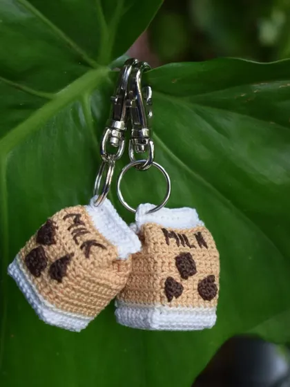 A pair of chocolate milk keychains hanging out together. This flavor is a classic choice for a sweet accessory.