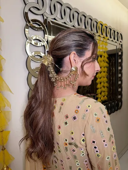 A side view of the textured ponytail, showing how the hair accessory connects to the earrings for a cohesive and unique look.
