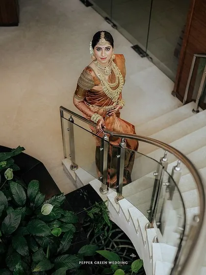 A stunning portrait of the bride descending a modern staircase, her traditional attire looking regal and elegant.