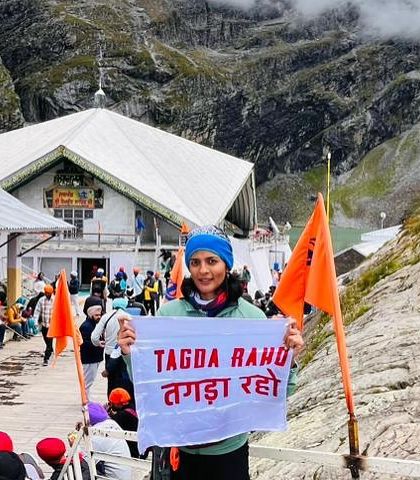 A member of our community proudly holds the Tagda Raho flag amidst a mountainous backdrop. This image represents the spirit of our tribe, taking the strength and resilience learned in our sessions to conquer personal challenges and adventures.