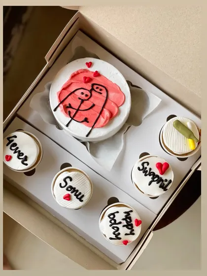 This adorable combo celebrates love with a bento cake showing two stick figures hugging, surrounded by five cupcakes. The cupcakes are personalized with names like 'Sonu' and 'Swapnil' and messages like '4ever' and 'happy bday'.