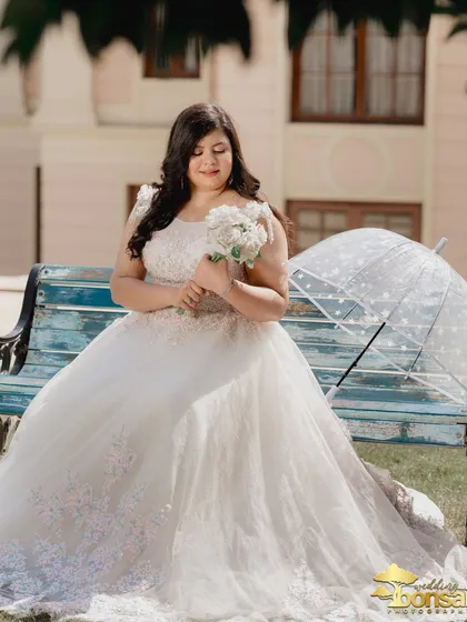 A solo portrait of the bride, looking serene and beautiful with her bouquet and umbrella. This shot highlights her elegance against the backdrop of the estate.