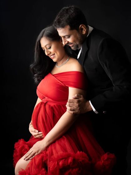 A close-up shot capturing the love and excitement. The vibrant red of her off-the-shoulder gown contrasts beautifully with his classic suit, making for a very romantic and formal couple's portrait.