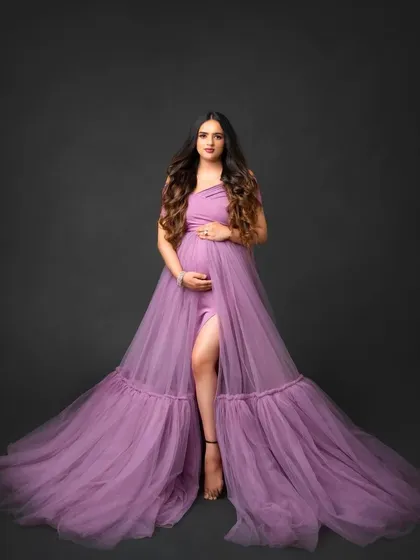 Feel radiant during your maternity shoot with our lavender gown. This studio portrait shows the dress's elegant drape and thigh-high slit, designed to beautifully highlight your baby bump.