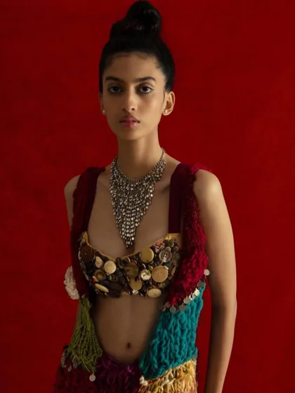 A closer view of the natural makeup and sleek top knot, which provides a clean counterpoint to the intricate details of the top and necklace.