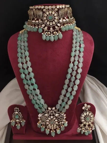 This pastel green Victorian set includes a choker with elephant motifs and a long beaded necklace with a peacock pendant. It's a beautiful blend of traditional designs.