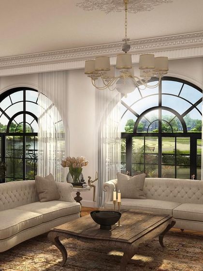 An intimate living space featuring classic Chesterfield sofas and arched windows that flood the room with light. The design creates a comfortable yet formal setting, perfect for conversation and entertaining.