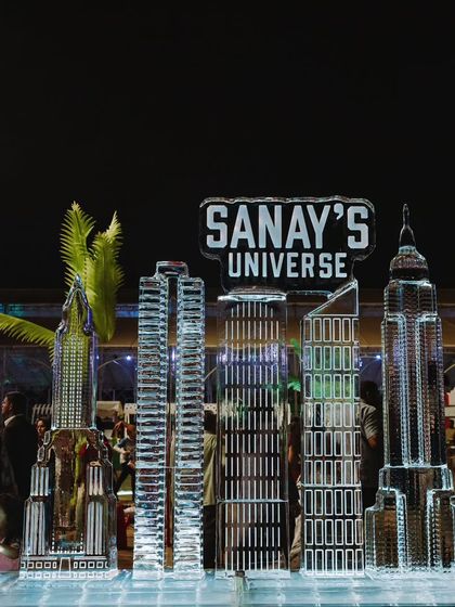An impressive ice sculpture of a city skyline with 'Sanay's Universe' branding. I use unique elements like ice sculptures to add a touch of luxury and 'wow' factor to events.