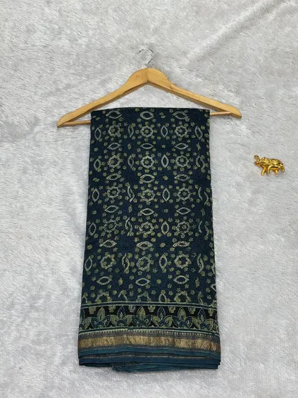 A beautiful Bagru printed saree in Chanderi silk, seen here hanging to display its intricate pattern. The dark color and traditional motifs make it a very elegant choice.