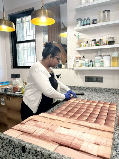 Here I am cutting a large loaf of soap into individual bars using our multi-bar cutter. This tool helps us ensure every bar is uniform in size.