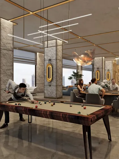 A sophisticated games room in a luxury development, featuring a beautiful wood-finished pool table. The space is designed for leisure and socializing, with stone-clad columns, modern lighting, and comfortable seating areas.