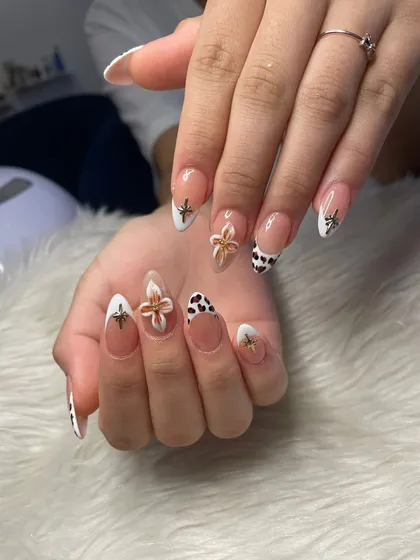 A close-up of the cow print and 3D flower details on this custom French manicure.