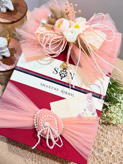 The right packaging elevates everything. Here, we've wrapped a designer box from Shantnu & Nikhil with soft peach tulle, a handcrafted floral bow, and a delicate pearl embellishment, turning a beautiful gift into an unforgettable experience.