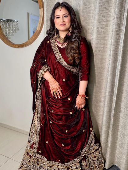 The sister of the bride looking absolutely regal in a deep red velvet ensemble. Her makeup is kept soft and natural to balance the richness of her outfit.