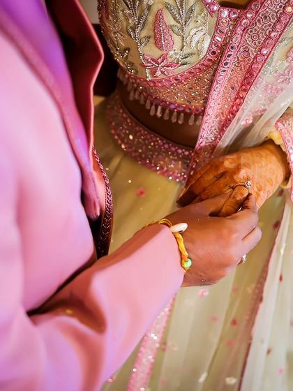 A close-up detail shot of a couple holding hands, focusing on the texture of their outfits and the gesture of their hands.