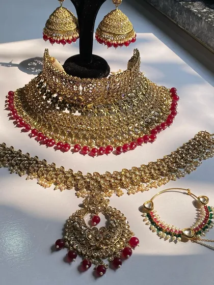 A full view of a ruby red bridal set, including a wide choker, mathapatti, maang tikka, and nath. I have this popular rental design available in multiple colors.