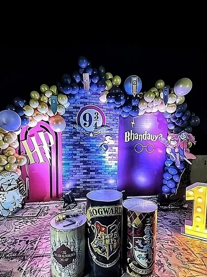 A magical Harry Potter themed birthday for a 10th birthday celebration. The decor features a Platform 9 3/4 backdrop, house crest props, and a balloon arch in house colors, all set up on a terrace for a nighttime event.
