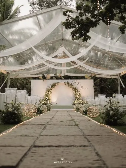 For this evening reception, we created a magical atmosphere with a transparent tent under the stars. The design focused on clean white florals, a stunning arched backdrop, and layers of romantic fairy lights, proving that minimalist decor can be incredibly impactful and breathtaking.